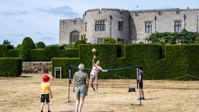 A family playing volleyball on the lawn in front of Chirk Castle.